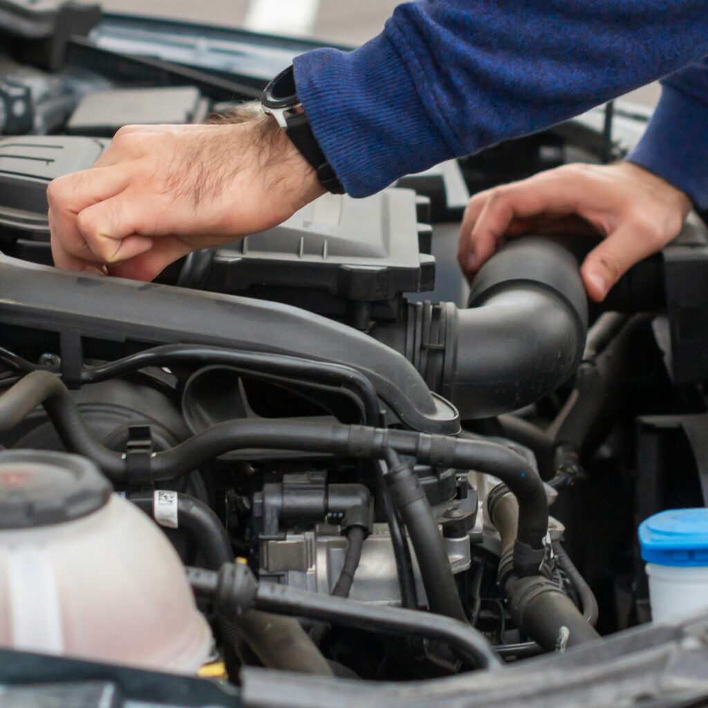 Closeup of mechanic hands checking motor under the hood in the broken car. Repairing of the vehicle
